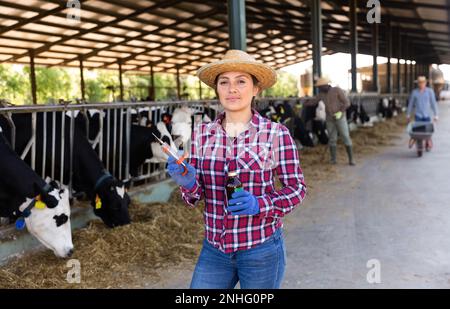 Tierärztin mit Spritze und Impfstoff in den Händen auf Milchviehbetrieb Stockfoto