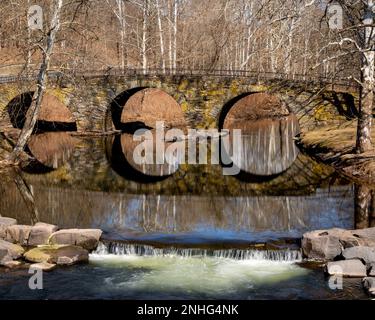 Kenoza Lake, NY - USA - 20. Februar 2023 Landschaftsblick auf die malerische Stone Arch Bridge mit drei Bögen, die sich über den East Branch des Callicoon erstreckt Stockfoto