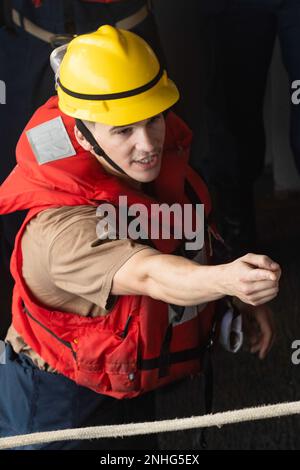 220730-N-CM110-1030 PAZIFIK (30. Juli 2022) – Boatswain’s Mate 3. Class Jose Mahiquesmartinez, aus San Juan, Puerto Rico, zeigt auf eine Linie, die ein starres Schlauchboot (RHIB) vom amphibischen Angriffsträger USS Tripoli (LHA 7) absenkt, 30. Juli 2022. Tripolis ist im US-amerikanischen 7.-Flottengebiet tätig, um die Interoperabilität mit Verbündeten und Partnern zu verbessern und als einsatzbereite Eingreiftruppe zur Verteidigung des Friedens und zur Aufrechterhaltung der Stabilität in der Region Indo-Pazifik zu dienen. Stockfoto