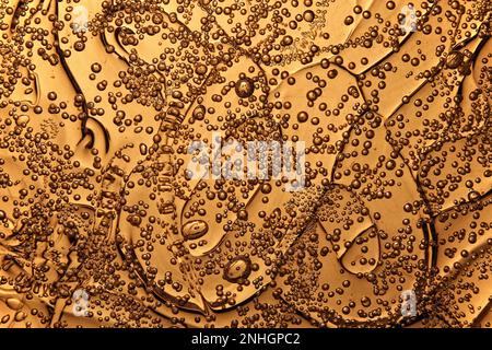 Makro-Vollbildansicht von Luftblasen, die in goldenem, geschmolzenem, transparentem Plexiglas eingeschlossen sind und eine einzigartige abstrakte Textur erzeugen Stockfoto