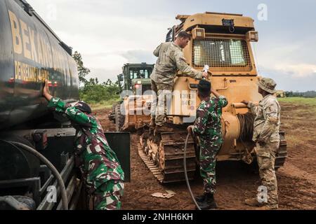 Soldaten der 130. Ingenieurbrigade, des 84. Ingenieurbataillons und des indonesischen nationalen Militärs betanken einen Dozer D6 während gemeinsamer Straßenreparaturen einer Feldübungsstraße auf der Python 1 Range, Baturaja, Indonesien, 29. Juli 2022, Als Teil von Garuda Shield 2022. Operation Pathways und eine langjährige, jährliche, bilaterale Militärübung zwischen dem US-Militär, der indonesischen Nationalarmee, verstärken die Verpflichtungen der USA gegenüber unseren Verbündeten und anderen regionalen Partnern und stärken die gemeinsame Bereitschaft und die Interoperabilität, gemeinsam zu kämpfen und zu gewinnen. Stockfoto