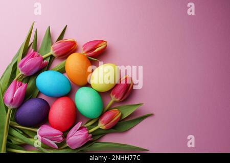 Frische bunte Tulpenblüten und ostereier auf rosa Hintergrund. Draufsicht mit Kopierbereich. Frohe ostergrußkarte. Stockfoto