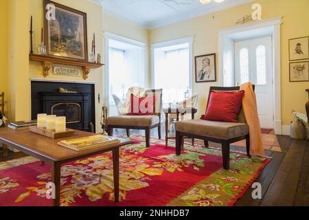 Teakholz Couchtisch und eklektische Stühle im Wohnzimmer mit Vermont Castings Kamin im alten Haus aus dem Jahre 1830. Stockfoto