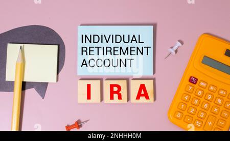 Auf hellblauem Hintergrund helle Holzblöcke und Würfel mit dem Text IRA Individual Retirement Account. Stockfoto