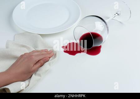 Eine Frau, die verschütteten Wein auf weißem Hintergrund säubert, Nahaufnahme Stockfoto