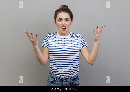 Wo liegt das Problem? Porträt einer gereizten, entzückten Frau, die ein T-Shirt trägt, die Hand hebt in Wut und schreit, warum, was willst du, streiten. Studioaufnahmen im Innenbereich isoliert auf grauem Hintergrund. Stockfoto