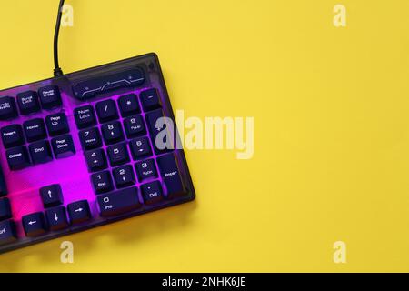 Moderne RGB-Tastatur auf gelbem Hintergrund, Draufsicht. Platz für Text Stockfoto