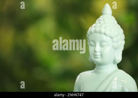 Buddha-Statue vor unscharfem grünen Hintergrund, Nahaufnahme. Platz für Text Stockfoto