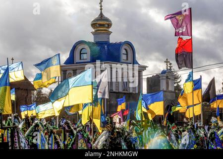 Blaue und gelbe ukrainische Nationalflaggen werden vom Wind geweht, und Blumen liegen auf Gräbern von Soldaten, die im Kampf gegen russische Streitkräfte getötet wurden, auf dem Friedhof von Lisove in der Hauptstadt der Ukraine. Da sich die Invasion der Ukraine durch die russischen Streitkräfte ihrem ersten Jahrestag nähert, ist die Zahl der Opfer sehr hoch, obwohl die genauen Zahlen unbekannt sind. Mindestens 13 ukrainische Soldaten haben ihr Leben verloren. Stockfoto