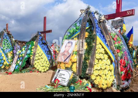 Porträts und blaue und gelbe ukrainische Nationalblumen liegen auf Gräbern von Soldaten, die im Kampf gegen die russischen Truppen getötet wurden, auf dem Friedhof von Lisove in der Hauptstadt der Ukraine. Da sich die Invasion der Ukraine durch die russischen Streitkräfte ihrem ersten Jahrestag nähert, ist die Zahl der Opfer sehr hoch, obwohl die genauen Zahlen unbekannt sind. Mindestens 13 ukrainische Soldaten haben ihr Leben verloren. Stockfoto