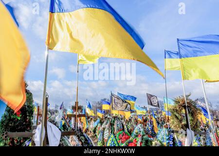 Kiew, Oblast Kiew, Ukraine. 21. Februar 2023. Blaue und gelbe ukrainische Nationalflaggen werden vom Wind geweht, und Blumen liegen auf Gräbern von Soldaten, die im Kampf gegen russische Streitkräfte getötet wurden, auf dem Friedhof von Lisove in der Hauptstadt der Ukraine. Da sich die Invasion der Ukraine durch die russischen Streitkräfte ihrem ersten Jahrestag nähert, ist die Zahl der Opfer sehr hoch, obwohl die genauen Zahlen unbekannt sind. Mindestens 13 ukrainische Soldaten haben ihr Leben verloren. (Kreditbild: © Dominika Zarzycka/SOPA Images via ZUMA Press Wire) NUR REDAKTIONELLE VERWENDUNG! Nicht für den kommerziellen GEBRAUCH! Stockfoto