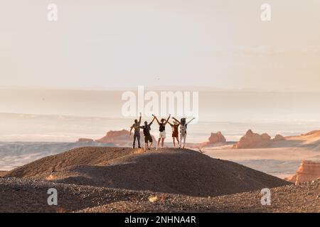 Eine Gruppe glücklicher Touristen steht mit offenen Armen am Aussichtspunkt der Wüste Stockfoto