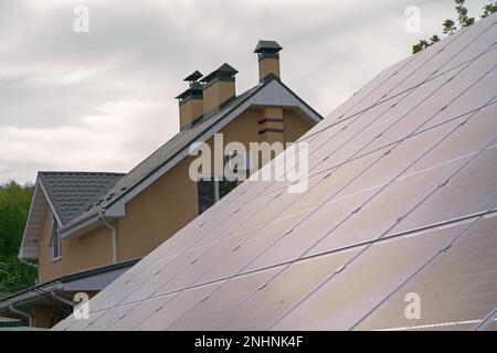 Nahaufnahme der Solarpaneele auf dem Giebeldach des historischen Gebäudes mit Schornstein. Privathaus mit Solarenergie. Stockfoto