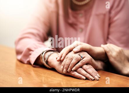 Mach dir keine Sorgen. Eine Krankenschwester, die eine ältere Frau behaglich an den Händen hält. Stockfoto