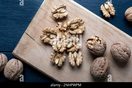 Walnusskerne und ganze Walnüsse auf einem Holzbrett. Draufsicht. Stockfoto