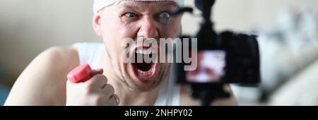 Porträt eines schreienden Bloggers, der Hanteln vor der Kamera hält Stockfoto