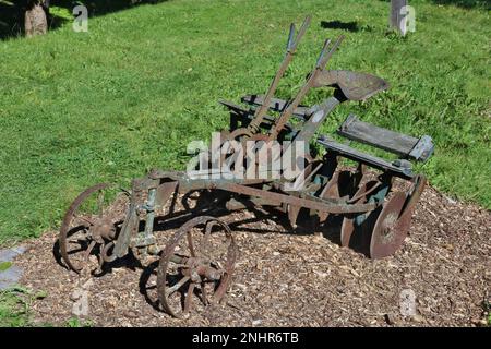 Ein alter rostiger Pflug im Garten eines Dorfhauses Stockfoto