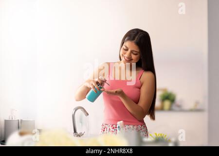 Frau, die ihre Hände im Badezimmer mit flüssiger Handwäsche reinigt Stockfoto