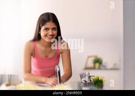Fröhliche junge Frau, die sich im Bad die Hände wäscht Stockfoto