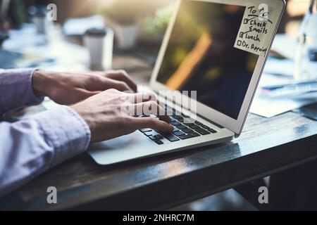 Mit seiner Arbeitsbelastung Schritt zu halten. Nahaufnahme eines unbekannten Geschäftsmanns, der in einem Café an einem Laptop arbeitet. Stockfoto