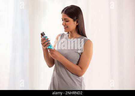 Eine Frau mit einer Flasche Mundwasser vor weißem Hintergrund Stockfoto