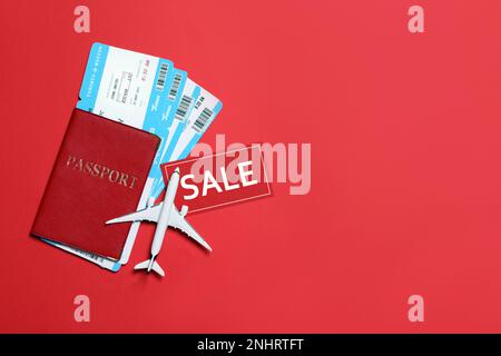 Flugtickets, Reisepass, Flugmodell und VERKAUFSKARTE auf rotem Hintergrund, flach liegend. Platz für Text Stockfoto