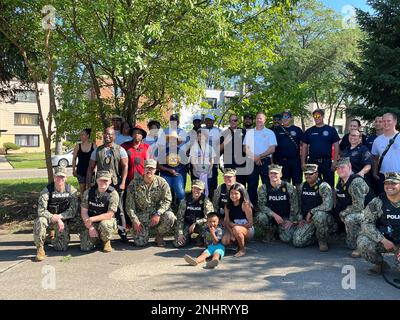 NORTH CHICAGO Il. (2. August 2022) Matrosen, die der Naval Station Great Lakes zugeteilt sind, und örtliche Ersthelfer posieren für ein Gruppenfoto während der National Night Out in North Chicago. National Night Out ist eine jährliche Kampagne zum Aufbau von Gemeinwesen, die Partnerschaften zwischen Polizei und Gemeinwesen und Nachbarschaftskameradschaft fördert. National Night Out verbessert die Beziehung zwischen Nachbarn und Strafverfolgungsbehörden und bringt gleichzeitig ein echtes Gemeinschaftsgefühl zurück. Stockfoto