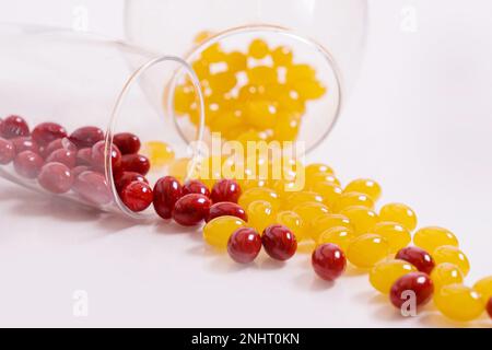 Tabletten, Kapseln zum Sehen. Rote und gelbe Vitamine werden aus dem Glas auf den Tisch gegossen. Dioptrien, Myopie, Weitsicht. Gesunder Körper, Herz und Knochen. Hochwertiges Foto Stockfoto