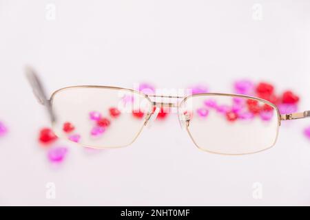 Tabletten, Kapseln zum Sehen. Vitamine in Form von Herzen mit Brille auf weißem Hintergrund. Dioptrien, Myopie, Weitsicht. Augenarzt, Optiker, Augengesundheit. Hochwertiges Foto Stockfoto