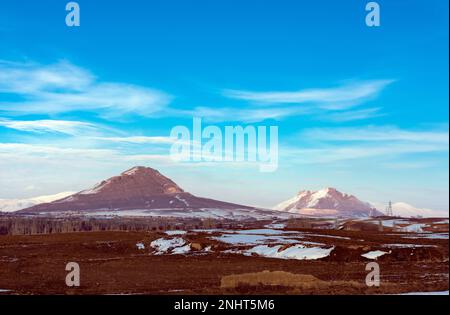 Schneebedeckte Berge an einem wolkigen Wintertag mit Wolken am blauen Himmel Stockfoto