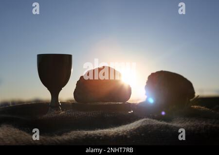 Heilige Kommunion Letztes Abendmahl Brot und Wein symbolisieren das heilige Blut und Fleisch Jesu Christi und strahlendes Sonnenlicht, Konzept der Fastenheiligen Woche Stockfoto