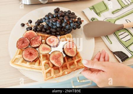 Wiener Waffeln mit Feigen und schwarzen Trauben zu Hause und im Restaurant. Gesundes, gesundes Frühstück für Vegetarier. Hochwertiges Foto Stockfoto