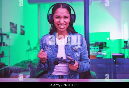 Gaming-Erfolg, Kopfhörersieger und nächtliche Frau in Neonlicht für Web-E-Sport. Porträt, Technologie oder weibliche Genz mit Gaming-Face Stockfoto