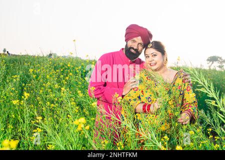 Portrait des jungen, glücklichen Punjabi-sikh-Paares, das zusammen auf dem Landwirtschaftsfeld steht. Stockfoto