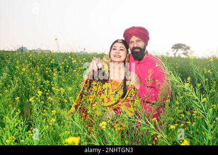 Glückliches junges Punjabi-sikh-Paar, das auf dem Landwirtschaftsfeld zusammensteht. Stockfoto