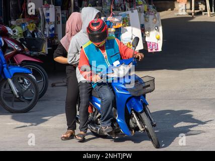 Ein Motorradtaxi fährt einen Mann in einer Kapuze und eine Frau mit einem Hijab Stockfoto