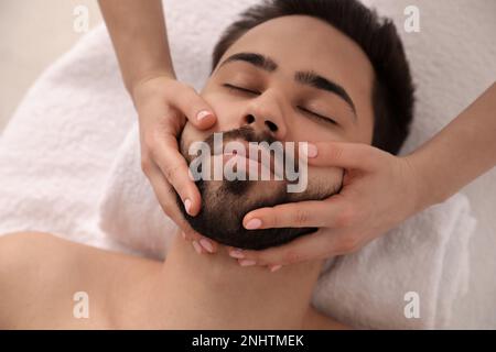 Junger Mann, der eine Gesichtsmassage im Schönheitssalon bekommt, von oben Stockfoto