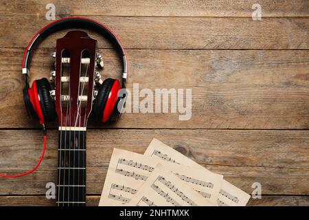 Komposition mit Gitarre und Noten auf Holztisch, flach liegend. Platz für Text Stockfoto