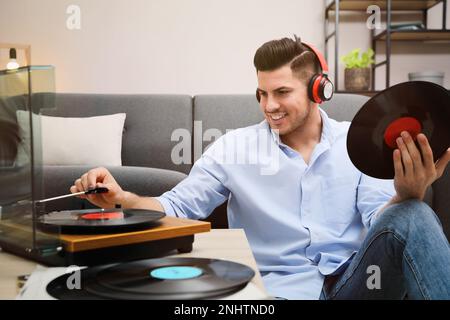 Glücklicher Mann, der zu Hause Musik mit Plattenspieler hört Stockfoto