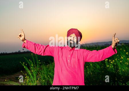 Punjabi sikh Mann tanzt Bhangra auf dem Landwirtschaftsfeld und feiert das Baisakhi- oder Vaisakhi-Festival. Stockfoto