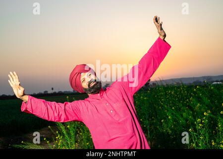 Punjabi sikh Mann tanzt Bhangra auf dem Landwirtschaftsfeld und feiert das Baisakhi- oder Vaisakhi-Festival. Stockfoto