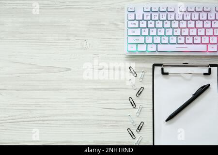 Flache Lagezusammensetzung mit moderner RGB-Tastatur auf weißem Holztisch, Platz für Text Stockfoto