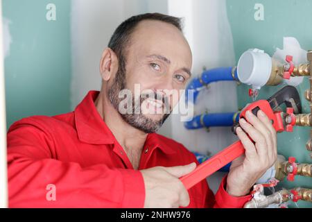 Klempner mit Schraubenschlüssel am Wasserrohr Stockfoto