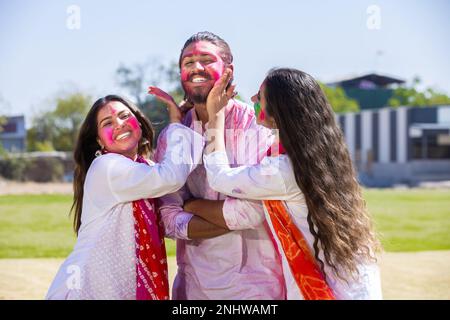 Fröhliche junge indische Familien spielen Fholi mit Farbpulver oder Gulal im Park. Stockfoto