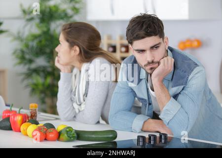 Ein geteiltes Paar mit gekreuzten Armen in der Küche Stockfoto
