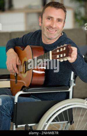 Ein glücklicher Behinderter, der Gitarre spielt Stockfoto