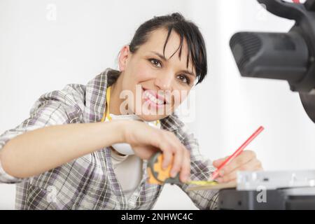 Taillenhochporträt eines geschickten jungen Holzarbeiters, der Maßband hält Stockfoto