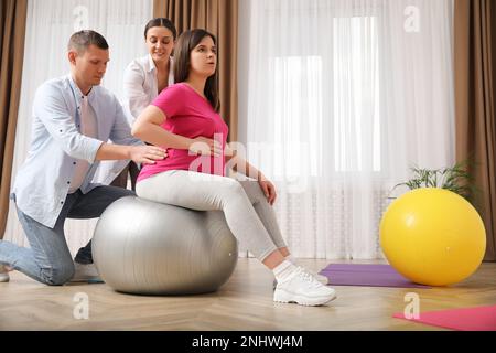 Schwangere Frau mit Ehemann und Hebamme im Fitnessstudio Stockfoto