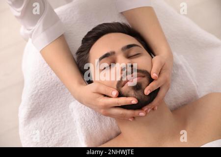 Junger Mann, der eine Gesichtsmassage im Schönheitssalon bekommt, von oben Stockfoto