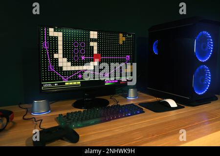 Moderner Computer und RGB-Tastatur auf Holztisch im Zimmer Stockfoto